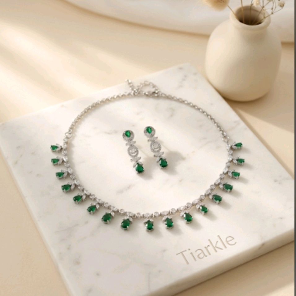 Tiarkle jewelry set featuring a silver-tone necklace and matching drop earrings with green and clear stones